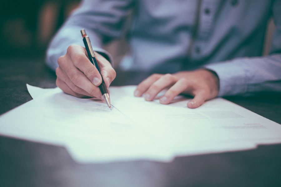 Hands signing bail paperwork at a table